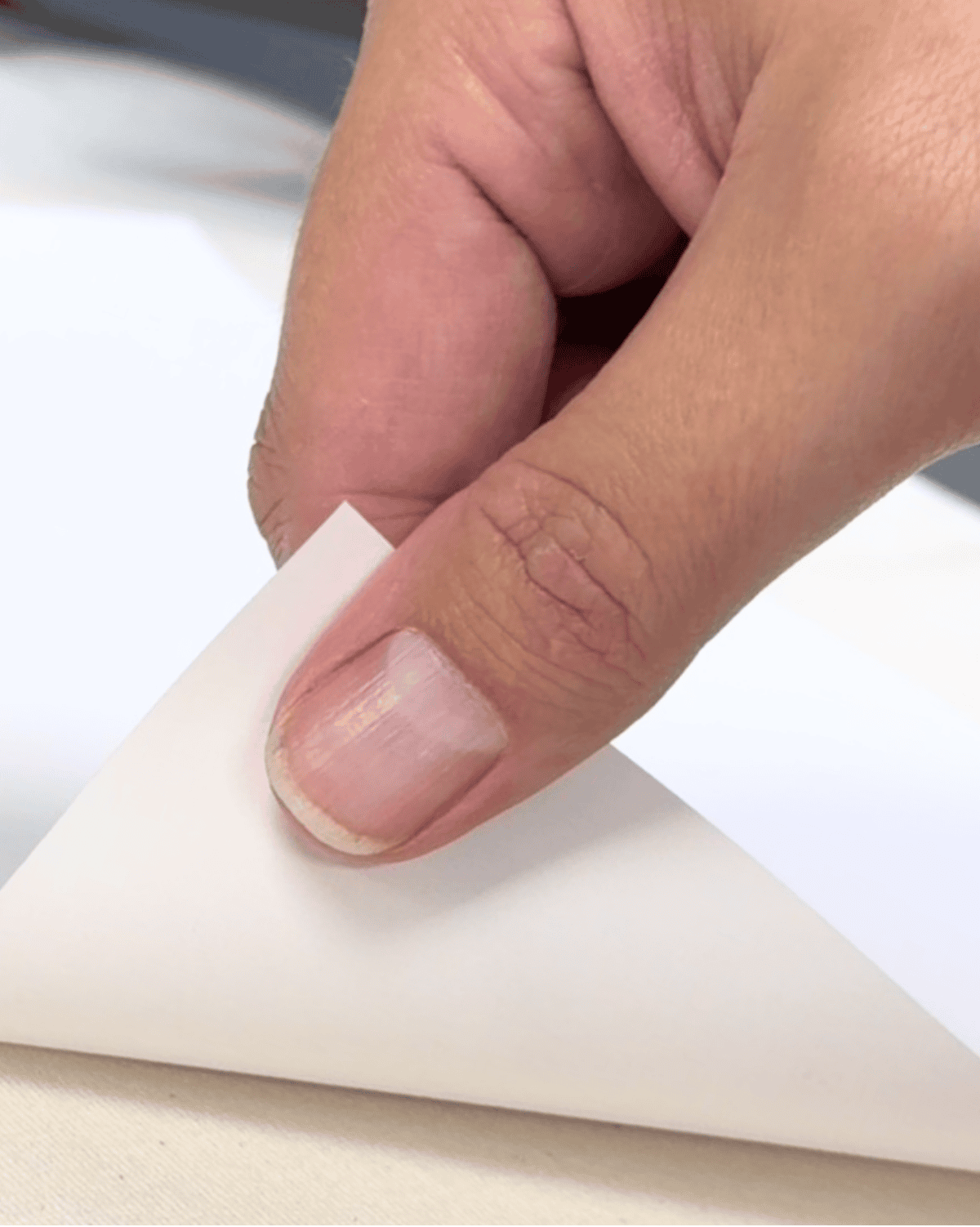 Fingers lifting a corner of transfer paper