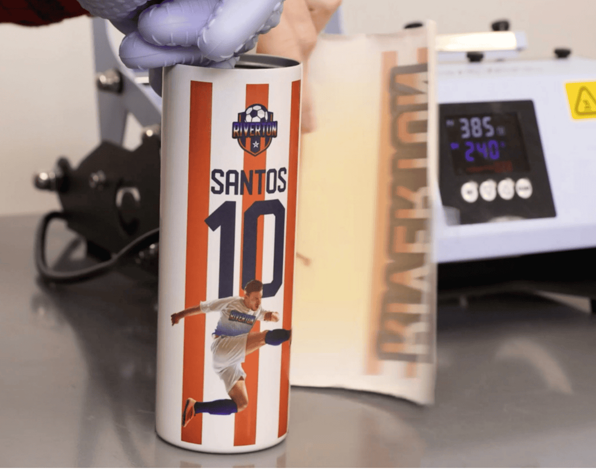 Personalized soccer tumbler being removed from a heat press